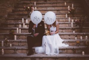 Newlywed couple sitting on steps and holding balloons