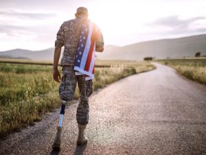 Rear View Of Young Amputee Soldier Walking Road Wearing American Flag