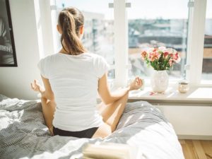 Beautiful woman practicing yoga in front of window of cozy apartment.Relaxation and mindfulness concept.